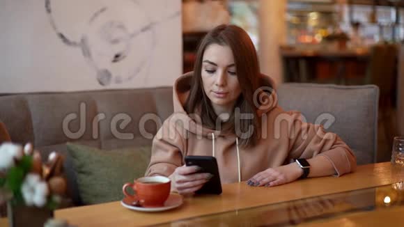 照片中年轻女子在舒适的咖啡店打电话视频的预览图
