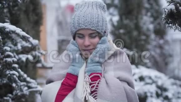 镜头接近年轻白种人的脸用冬天的手套和微笑触摸着脸积极向上视频的预览图