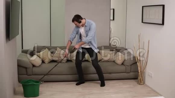 人家务和家务的概念快乐的人戴着耳机拖把清洁地板在家跳舞使用视频的预览图