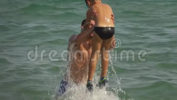 年轻的爸爸扑通一声把男孩扔进海水里视频的预览图