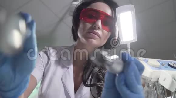 牙科诊所的病人观点布鲁内特高加索女性口腔医生使用仪器和固化灯来视频的预览图