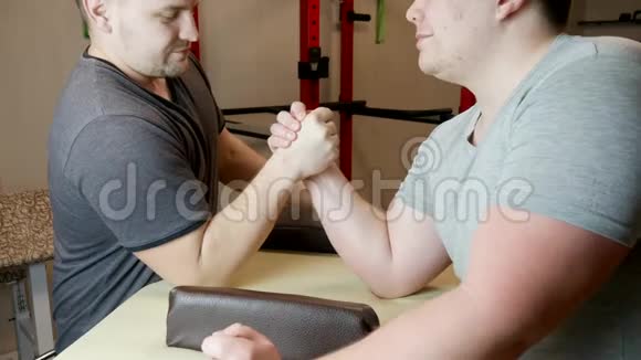 两个肌肉发达的男人在测量力量健身房里的手臂摔跤视频的预览图