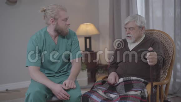 一幅白人男子的画像他在疗养院里听着退休人员心烦意乱的故事手牵着手男护士视频的预览图