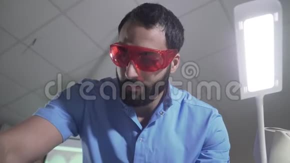 严肃的中东男子穿着蓝色制服戴着防护眼镜准备病人探视英俊的肖像视频的预览图