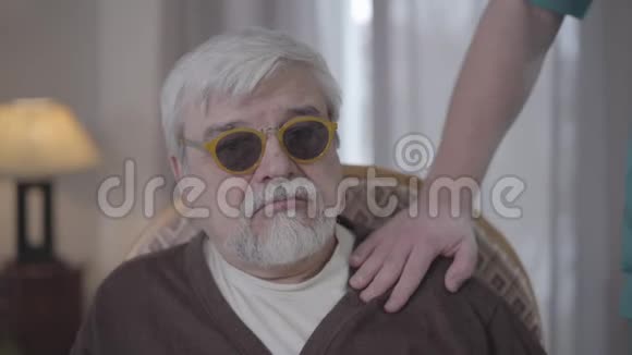 一位失明的成年男子牵着一位面目全非的男护士的手微笑着快乐老年残疾人画像视频的预览图