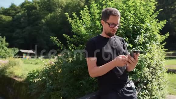 男人在户外花园里使用智能手机视频的预览图
