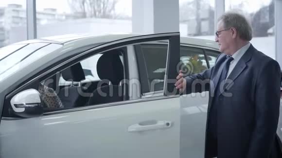 镜头接近满足成熟白人男子的脸关上车门触摸新车并显示拇指视频的预览图