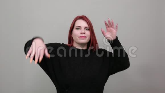年轻的红头发的胖女人穿着黑色毛衣滑稽的女人手举在头上视频的预览图
