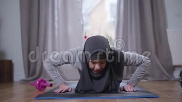 穆斯林妇女戴头巾的肖像在家里被推倒自信的强壮女人在室内运动服装生活方式视频的预览图
