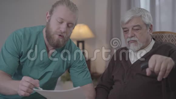 白种人男护士的特写向成熟的退休人员解释文件事项协助长者护理院工作的男子视频的预览图