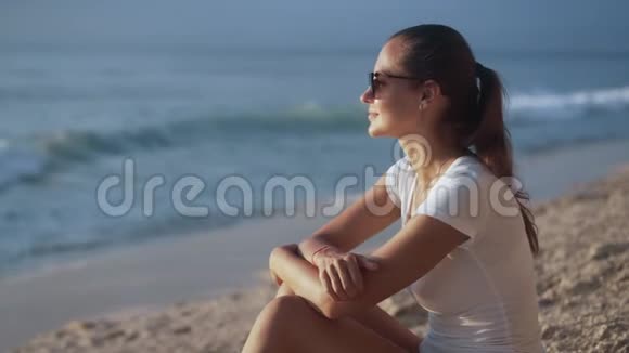 美丽微笑的女人戴着太阳镜在日落时看着大海的肖像视频的预览图