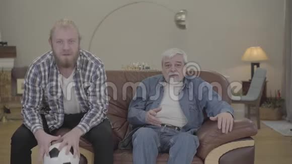 失望的白人父子在室内观看足球比赛的肖像成年男性和老年男性退休人员视频的预览图