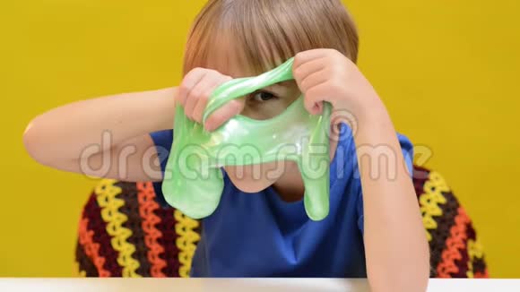 有趣的金发男孩玩黏液为孩子们准备的抗压力玩具可爱的孩子享受黏液玩具视频的预览图