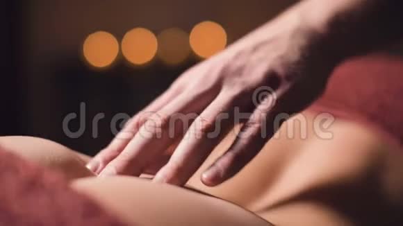 专业理疗师按摩师为女性患者做腰椎按摩的手部特写视频的预览图