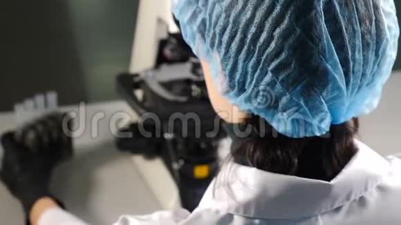 医学实验室微生物研究中使用显微镜的女性科学家的后视图研究员视频的预览图