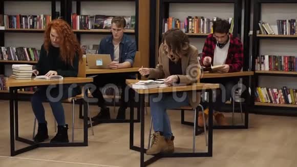 一群学生在大学图书馆准备考试两个漂亮的女人做笔记两个同伴在读书视频的预览图