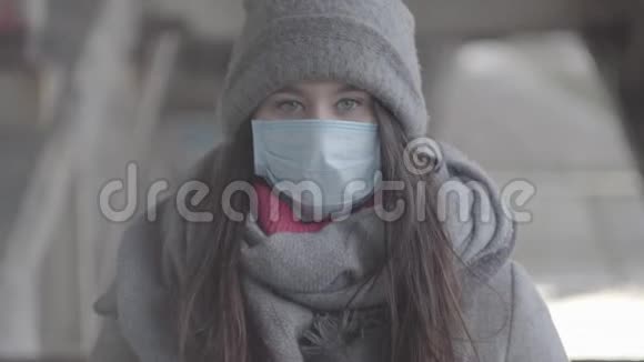 登录2穿着冬装戴着防护面罩看着镜头的深褐色灰眼女孩的肖像年轻的高加索人视频的预览图