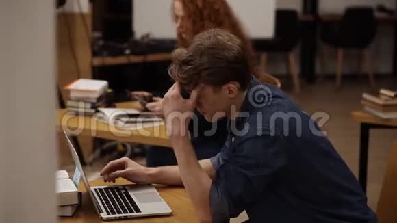 图书馆使用笔记本电脑的专注年轻人侧视图英俊的欧洲留学生视频的预览图