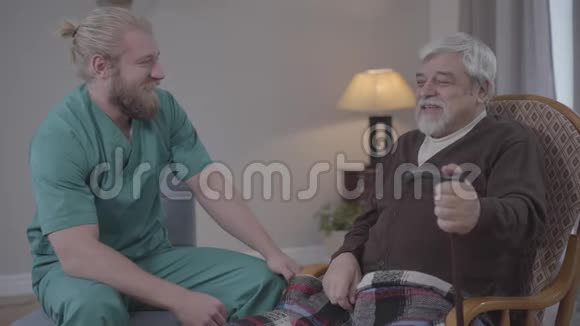 正面男护士和退休人员谈笑的侧观白种人成年人和成熟男人度过快乐的夜晚视频的预览图