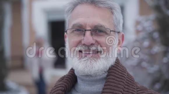 戴着眼镜的英俊优雅的男人对着镜头微笑的特写镜头白发高加索退休老人摆姿势视频的预览图