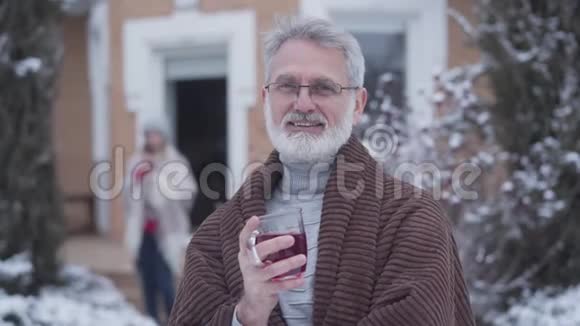 优雅的高加索人用茶杯摆在户外的肖像戴眼镜的优雅灰发男性退休人员视频的预览图