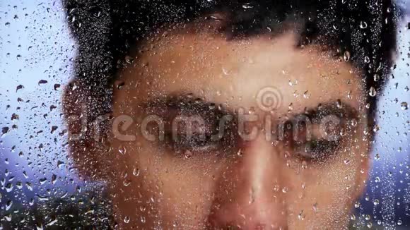 一场雨后白种人的外表透过潮湿的窗户看着特写镜头视频的预览图