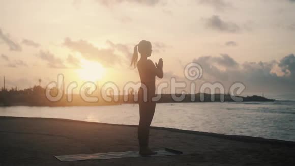 沙滩上的苗条女子训练日出时做瑜伽姿势视频的预览图