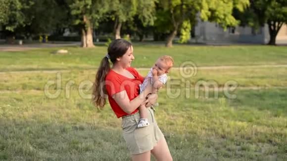 微笑的妈妈和宝宝在绿色公园玩得开心视频的预览图