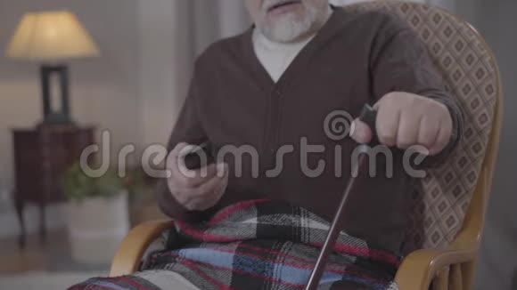无法辨认的愤怒老人用遥控器切换频道并与电视交谈安老退休人士休息视频的预览图
