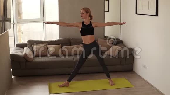 穿黑色运动服的瘦女孩在家中练习瑜伽练习个人练习视频的预览图