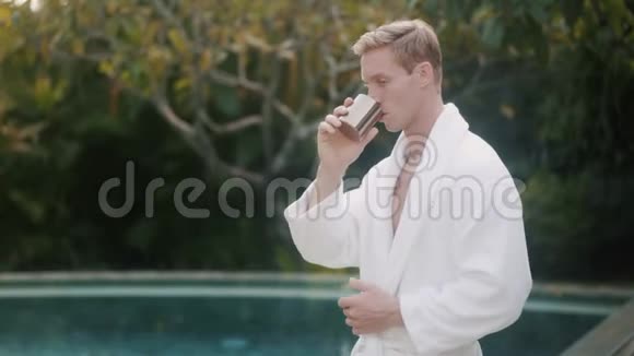 穿着浴衣的年轻人在游泳池附近喝咖啡视频的预览图