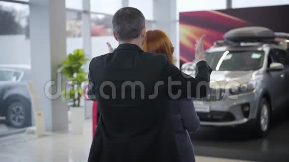 一个成功的白种人在汽车经销店给妻子制造惊喜年轻英俊的商人视频的预览图