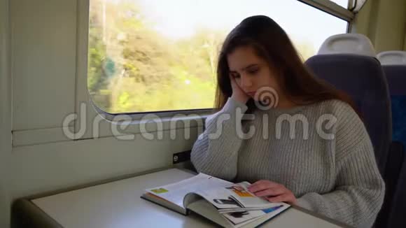 一位美丽年轻的女士坐火车旅行读一本书视频的预览图