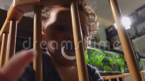 可爱的小男孩嘴里放着奶嘴坐在游戏厅里视频的预览图