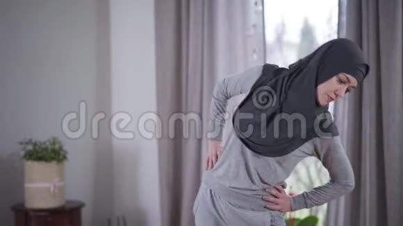 年轻穆斯林妇女在家的工作戴头巾的女人在室内弯腰生活方式运动锻炼视频的预览图