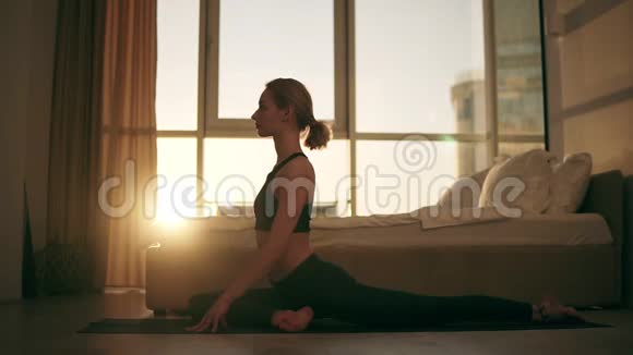 鸽子的姿势有魅力的白种人女人在家练习瑜伽坐在地上的黄色垫子上训练视频的预览图