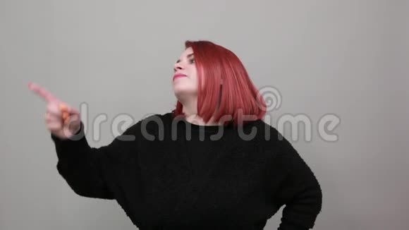 年轻的红头发胖女人穿着黑色毛衣时髦的女人三指微笑视频的预览图