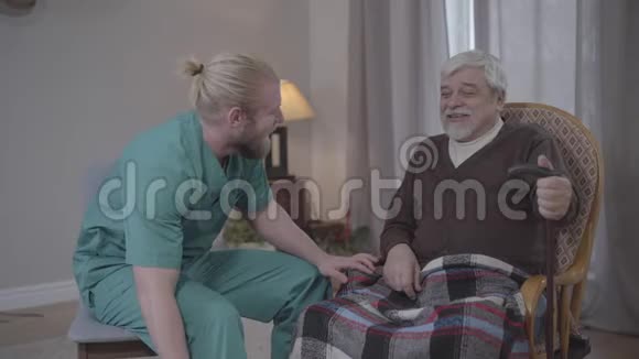 快乐老人在室内与男护士谈笑风生的画像成年白种人退休后在视频的预览图