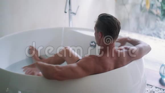 肌肉发达的运动员在家里的大浴缸里休息侧视视频的预览图
