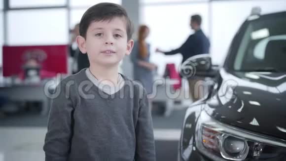 快乐的小白种人男孩在汽车经销店出现的画像在后台做交易的父母视频的预览图