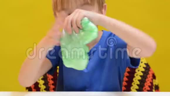 快乐男孩在白桌上玩黏液有趣的流行口香糖游戏孩子喜欢用黏液玩具视频的预览图