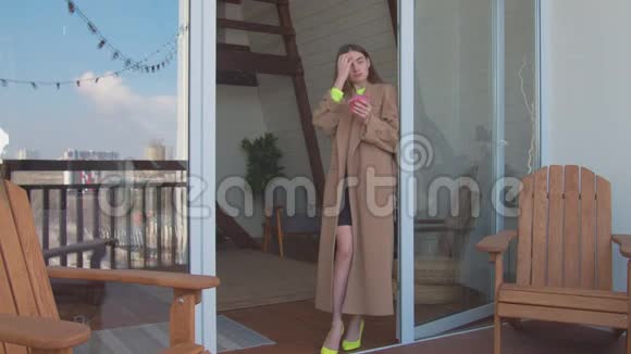 带着早咖啡的女人在阳台欣赏风景视频的预览图