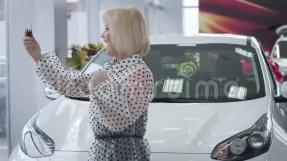 开朗成熟的白种人女人在新车前拿着车钥匙跳舞积极成功的女商人视频的预览图