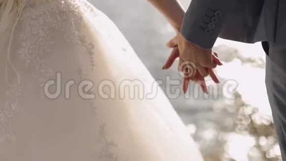 新婚夫妇站在海边他们互相握手新郎和新娘视频的预览图