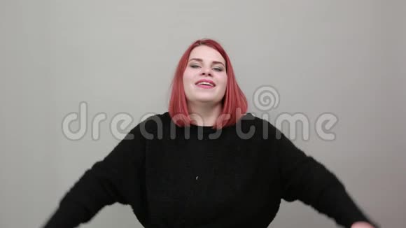红发女郎穿着黑色毛衣幸福的女人抬起手微笑地摇着她们视频的预览图
