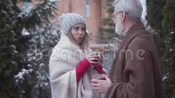 年轻美丽的高加索女人和白发男子在户外喝茶的肖像微笑女孩和高级退休人员视频的预览图
