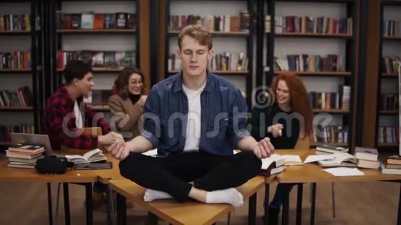 学习期间图书馆里的混乱年轻的男学生在桌上沉思在他摆姿势的时候视频的预览图