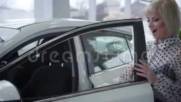 积极的白种人高级妇女打开门坐在司机座位上微笑成功的女士买新车视频的预览图