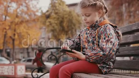 金色秋天孩子们在街上玩智能手机视频的预览图