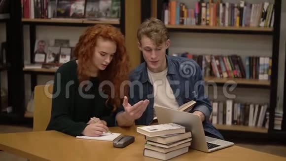 红头女孩和帅哥欧洲学生一起学习在学生图书馆看书讨论和准备视频的预览图